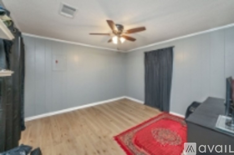 A room with a ceiling fan and a red rug on the floor.