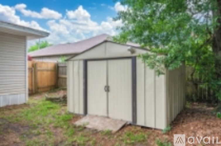 A shed with a brown door is situated in a yard.