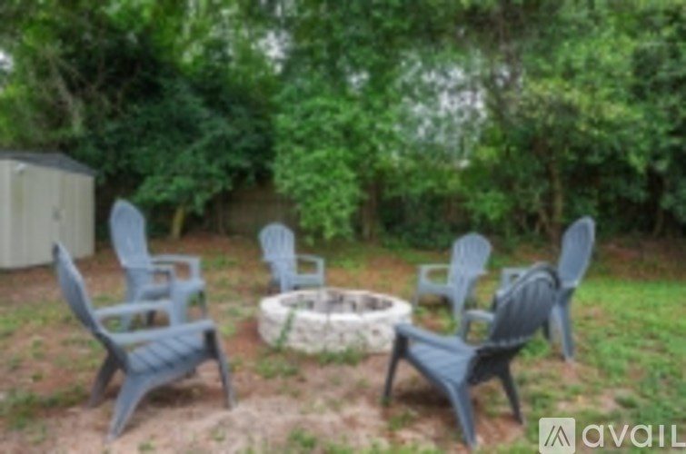 A set of four chairs and a fire pit are arranged in a yard.