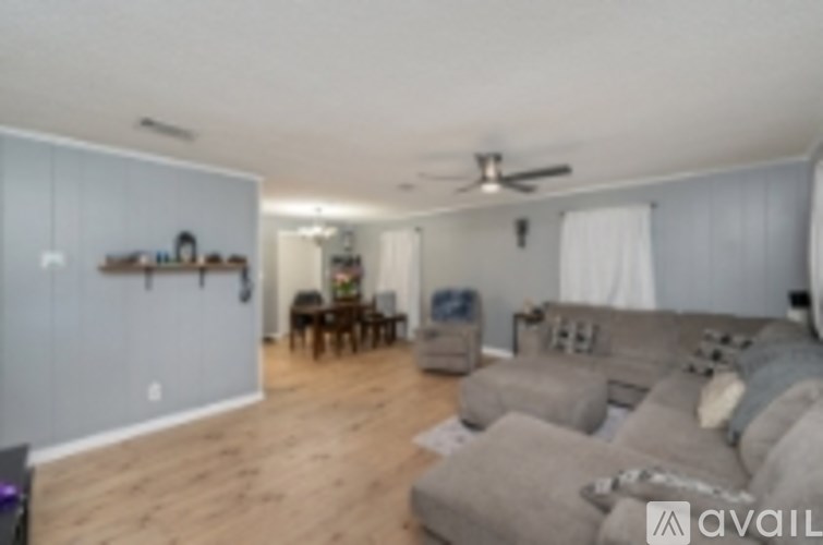 A living room with a grey couch and a fan on the ceiling.