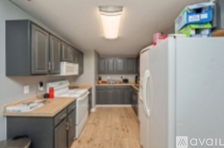 A kitchen with a white fridge and wooden floor.