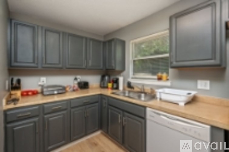 A kitchen with dark grey cabinets and a wooden counter top.