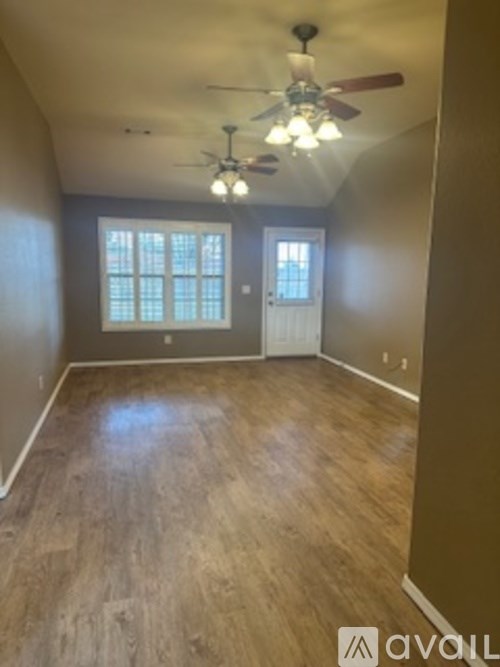 A room with a ceiling fan and wooden flooring.