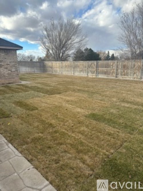 A backyard with a fence and a stone building.