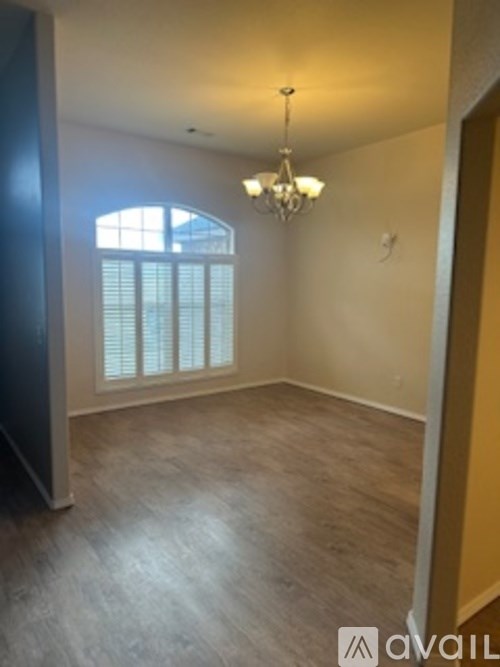 A room with a chandelier and a window with blinds.