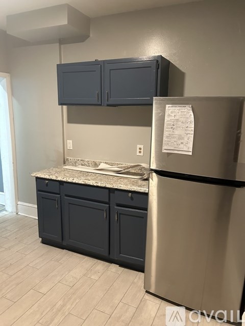 A kitchen with a stainless steel refrigerator and dark blue cabinets.
