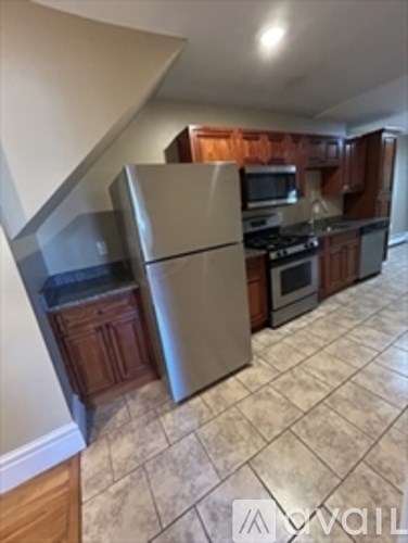 A kitchen with a stainless steel refrigerator and wooden cabinets.