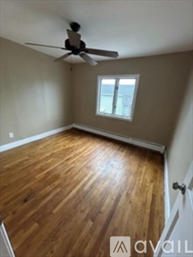 A room with a ceiling fan and wooden flooring.
