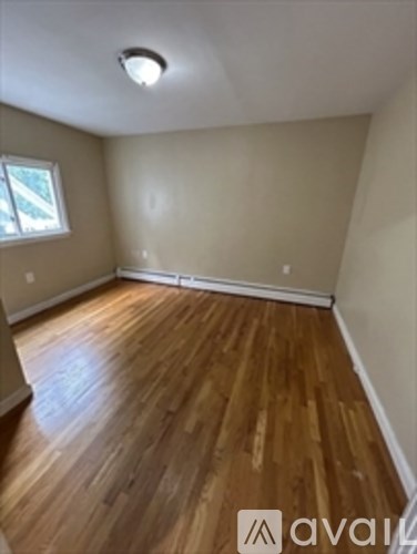A room with wooden flooring and a window.