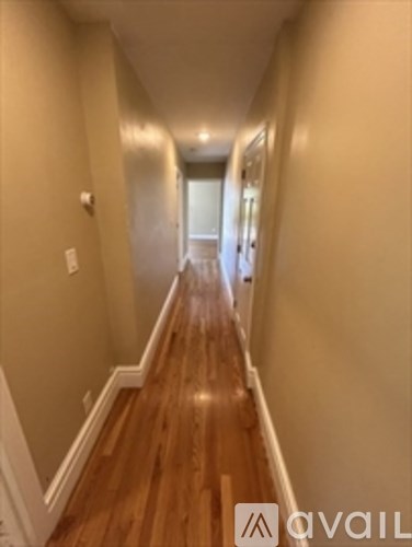 A long hallway with wood floors and white walls.