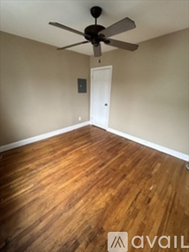 A room with a ceiling fan and wooden flooring.