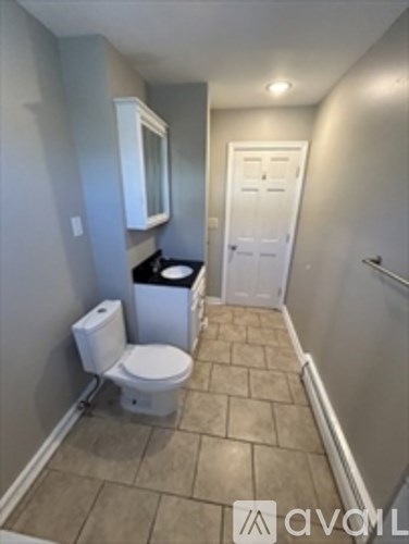 A bathroom with a toilet, trash can, and a door.