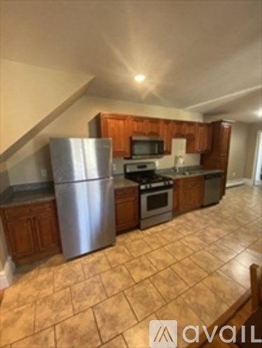 A kitchen with a stainless steel refrigerator and wooden cabinets.