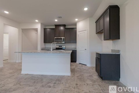 A kitchen with a white counter and dark brown cabinets.
