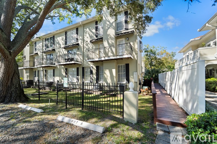 A row of white apartment buildings with balconies and black railings.