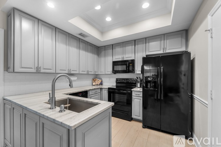 A kitchen with black appliances and grey cabinets.