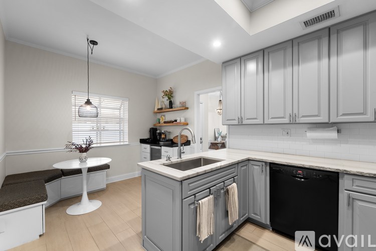 A kitchen with a black dishwasher and grey cabinets.