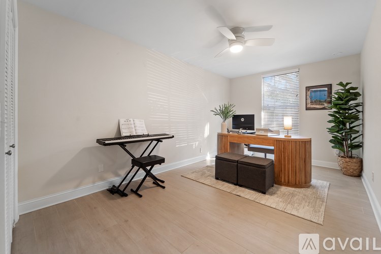 A room with a desk, chair, and a plant.