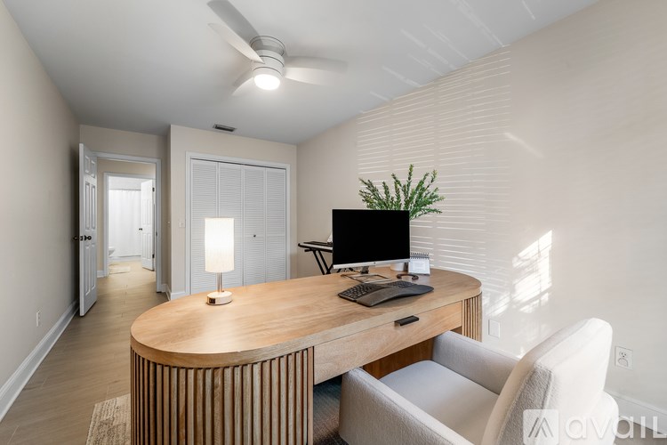 A room with a desk, chair, and a plant.