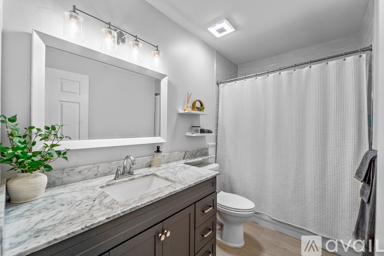 A bathroom with a marble countertop and a white shower curtain.