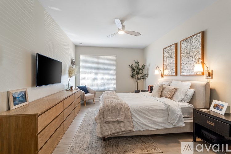A bedroom with a large bed, a TV, and a ceiling fan.