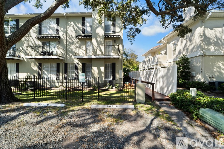 A white apartment building with balconies and a black fence.