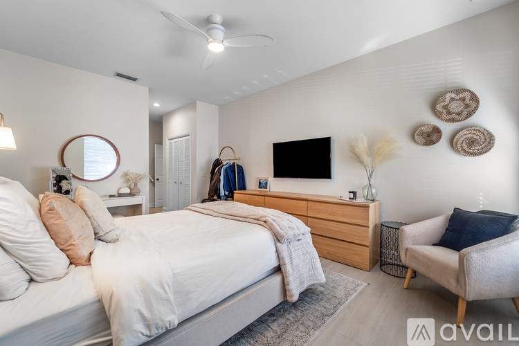 A bedroom with a bed, a chair, and a ceiling fan.