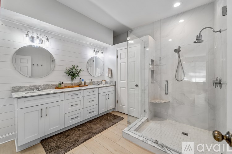 A bathroom with a marble countertop and white cabinets.
