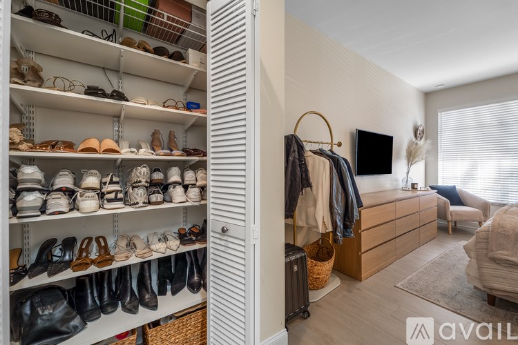A room with a shoe rack and a chair.