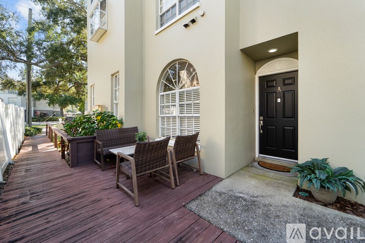 A wooden deck with a table and chairs is in front of a house.