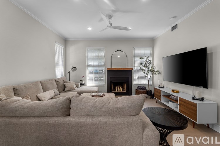 A living room with a grey sofa, a fireplace, and a television on a stand.