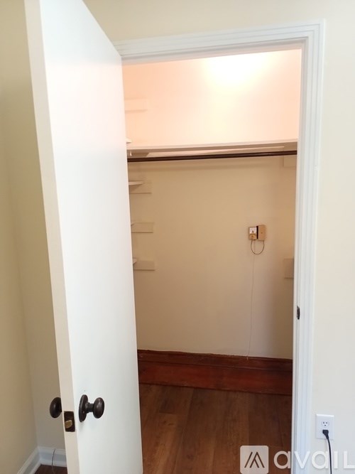 A white door is open to a room with a wooden floor.