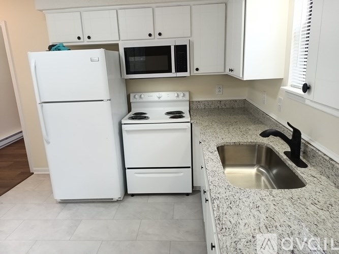 A white kitchen with a fridge, stove, and microwave.