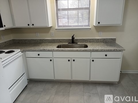 A kitchen with white cabinets and a granite countertop.