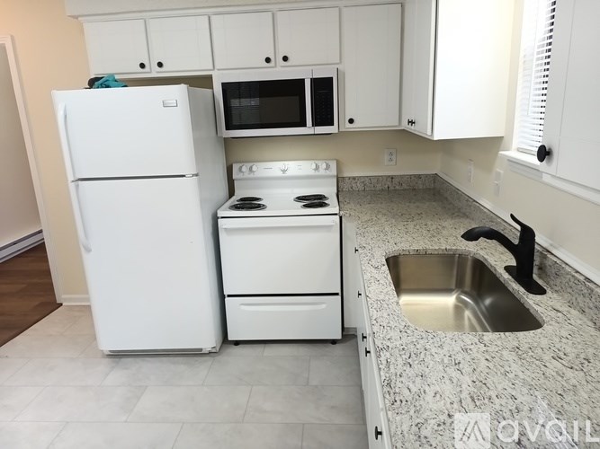 A white kitchen with a fridge, oven, and microwave.