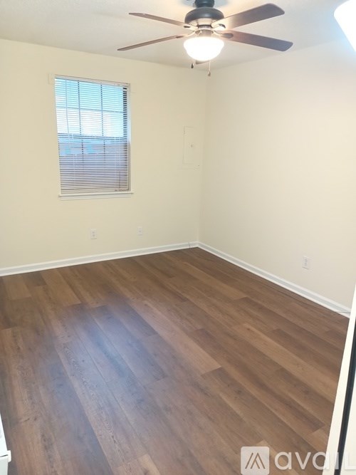 A room with a ceiling fan and wooden flooring.