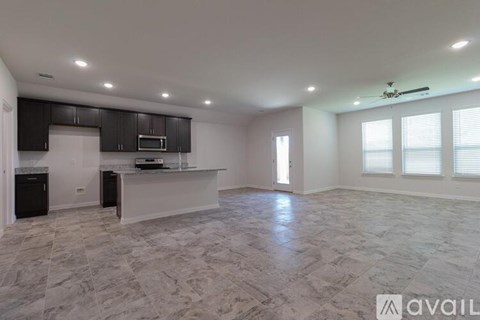 A spacious kitchen with a marble floor and a ceiling fan.