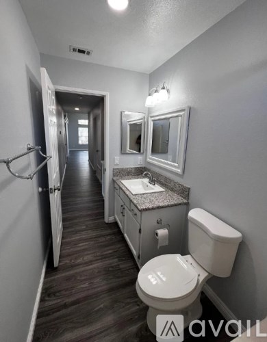 A bathroom with a toilet, sink, and mirror.