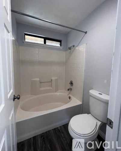 A small bathroom with a toilet, tub, and window.