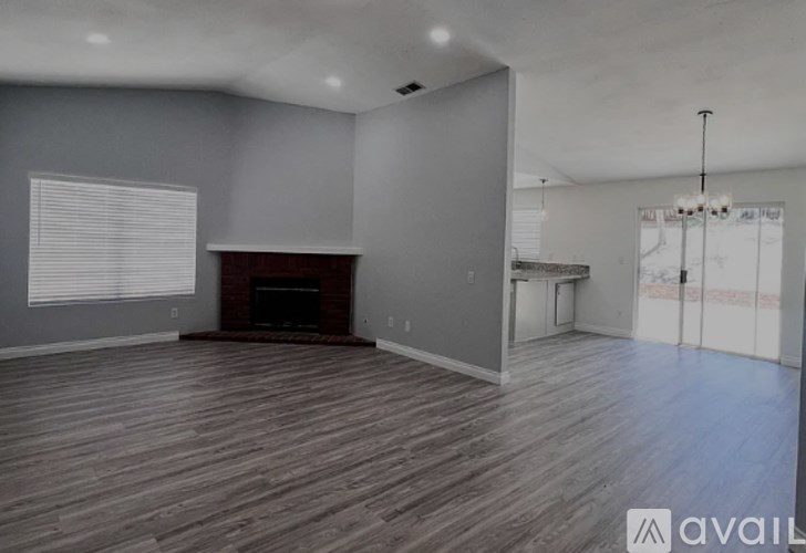 A spacious living room with wood flooring and a fireplace.