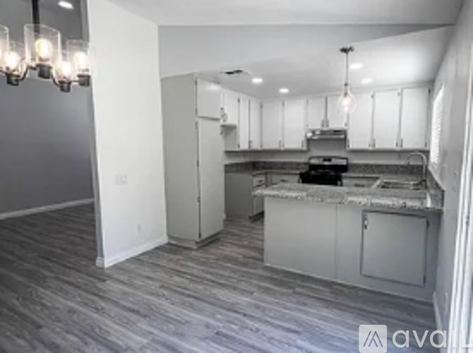 A kitchen with white cabinets and a wooden floor.