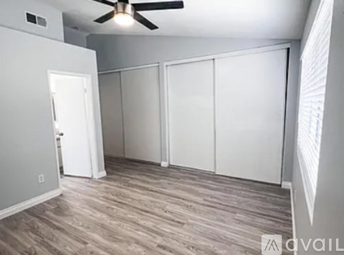 A room with a ceiling fan and sliding doors.