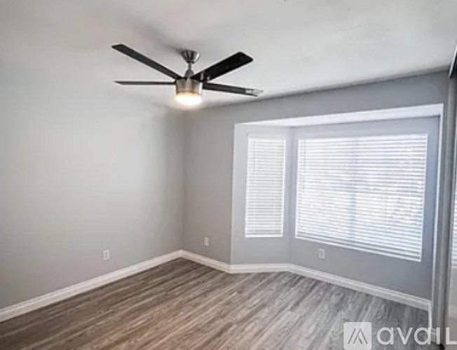 A room with a ceiling fan and a window with blinds.