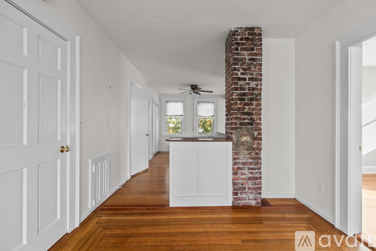 A long hallway with a brick pillar and a ceiling fan.