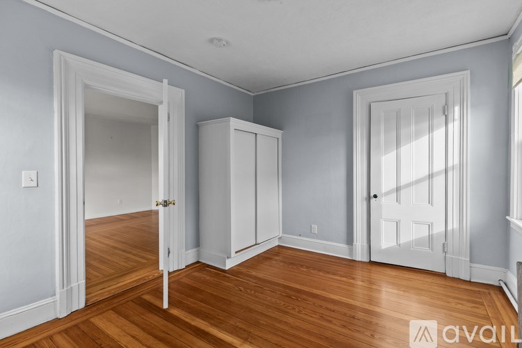 A room with wooden floors and white doors and cabinets.
