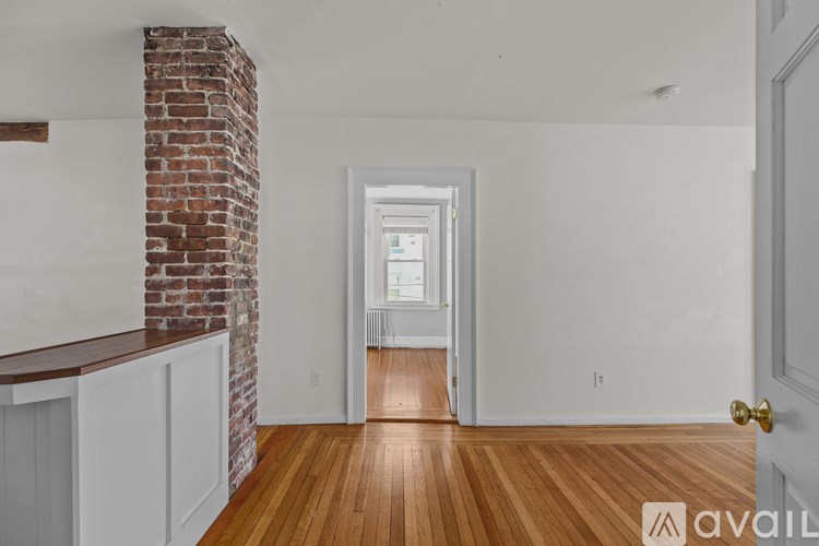 A room with a brick column and wooden floors.