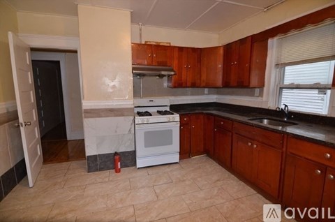 A kitchen with a white stove top oven and wooden cabinets.