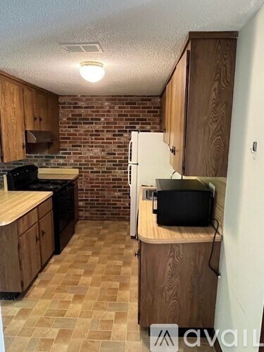 A kitchen with wooden cabinets and a brick wall.