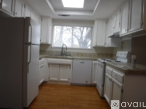 A kitchen with white cabinets and a wooden floor.