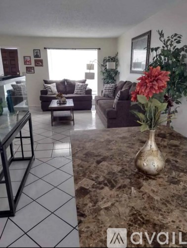 A living room with a couch, coffee table, and a vase of flowers.